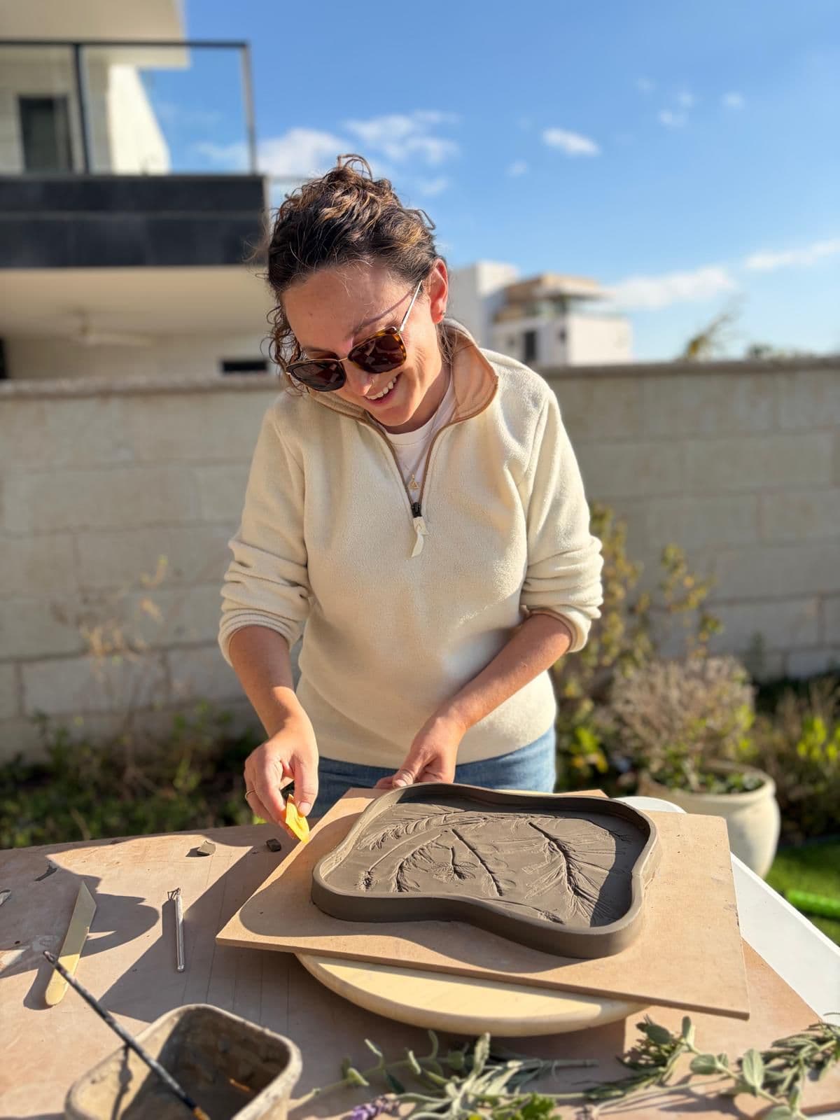 Metuka engraving a botanical pattern on a clay tray